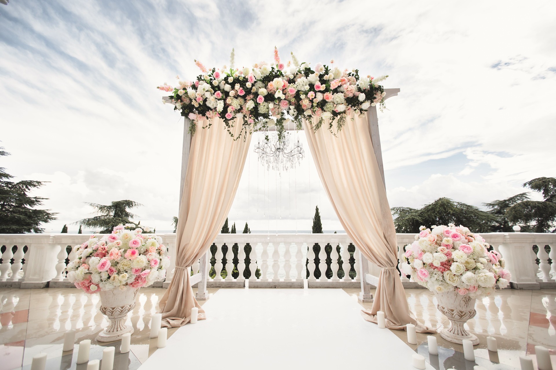 The wedding arch decorated with flowers stands in the luxurious area of the wedding ceremony.